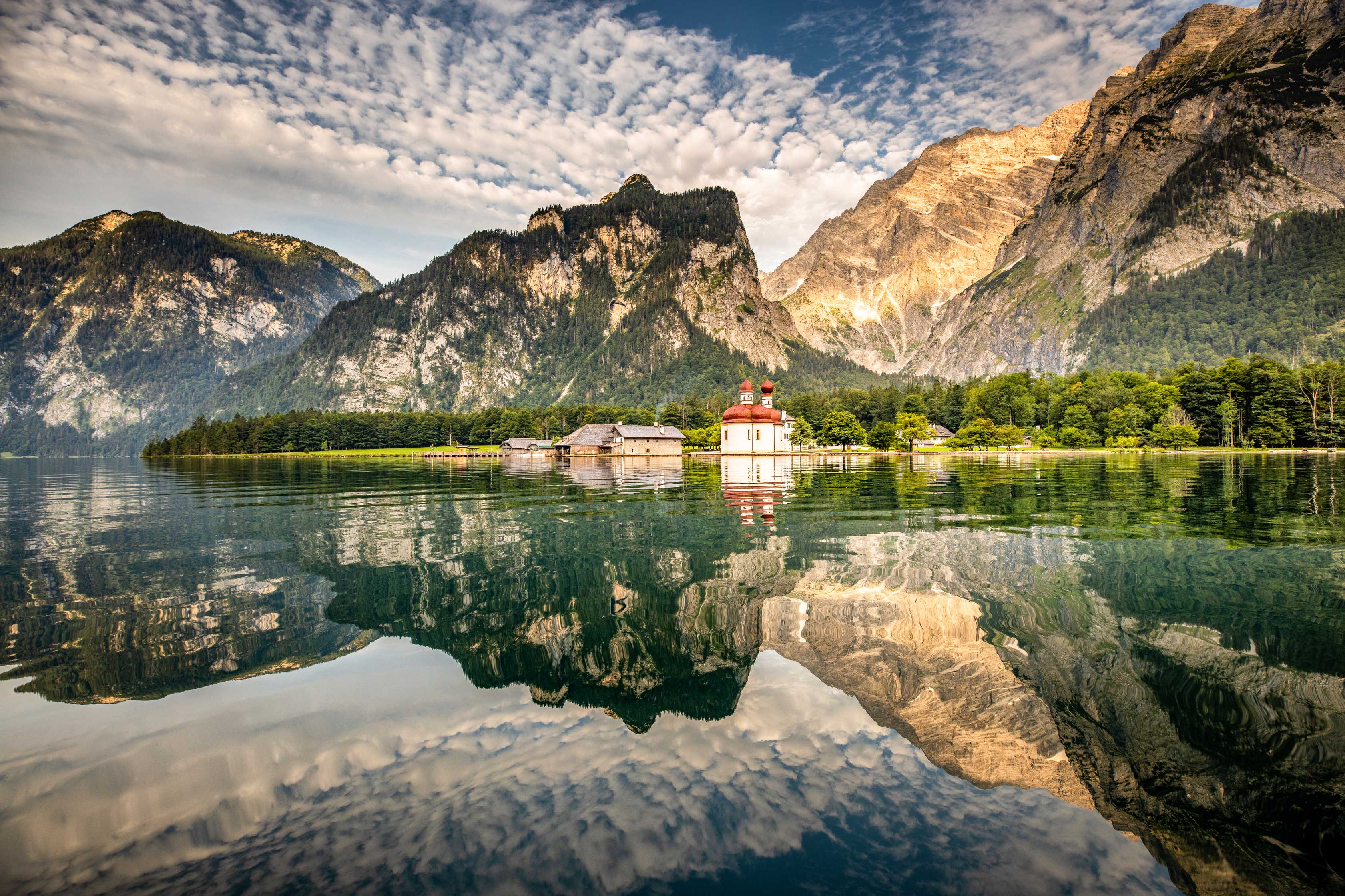 Der Königssee. Die Berge und die Wolken spiegeln sich im Wasser.