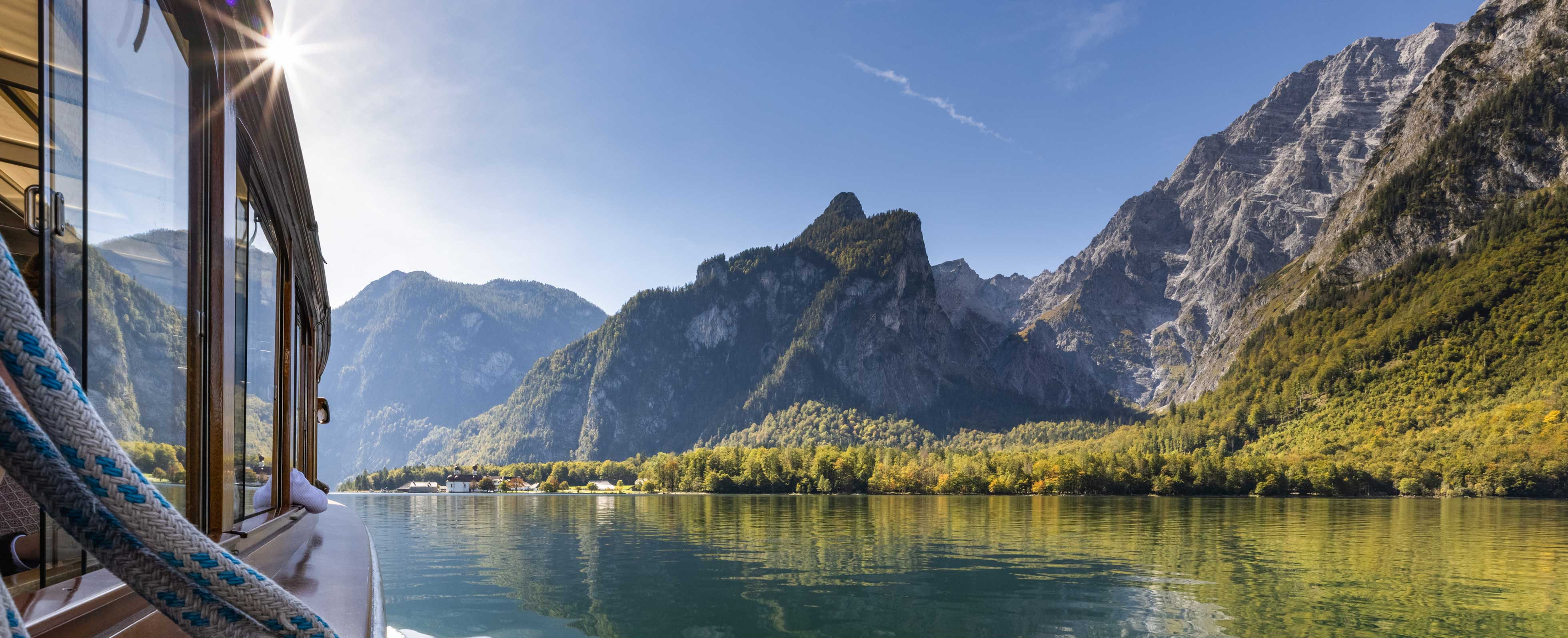 Ein Schiff fährt auf einem See, mit Bergen im Hintergrund